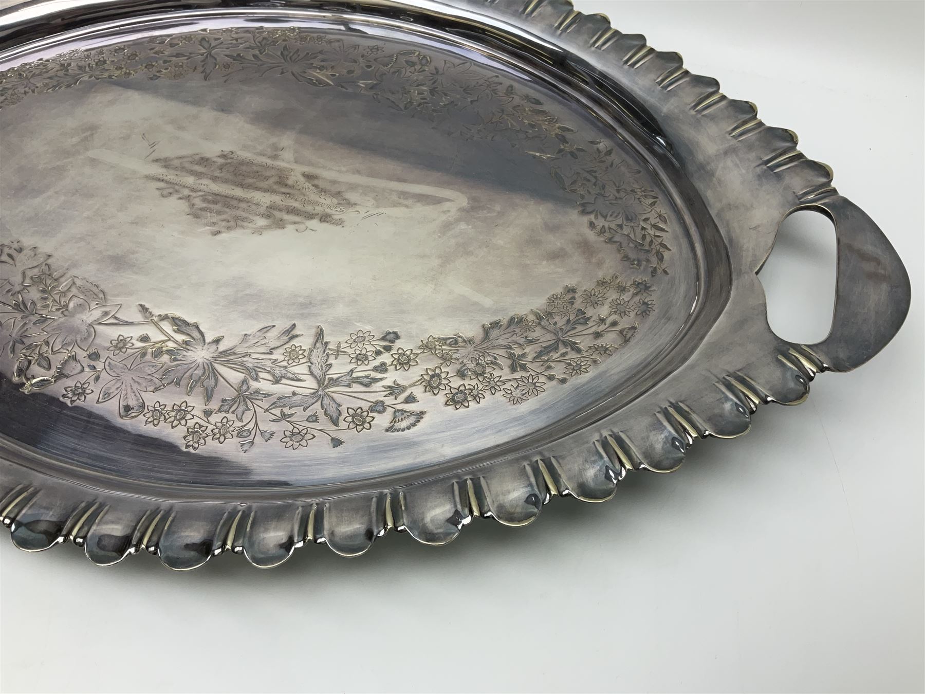 Oval silver plate twin handled tray, egg and dart edge, engraved with floral springs surrounding an central inscription, L65cm