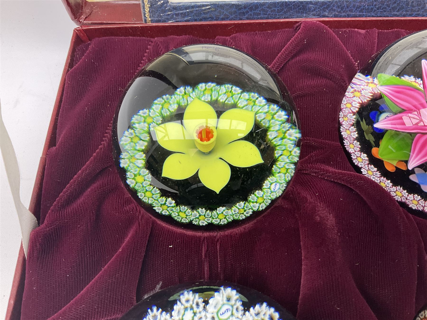 Set of four Caithness paperweights titled Four Seasons, in presentation box with certificate, designed by Colin Terris and made by William Mason, each internally decorated with a seasonal flower within a millefiori cane work garland, numbered 128 of 500