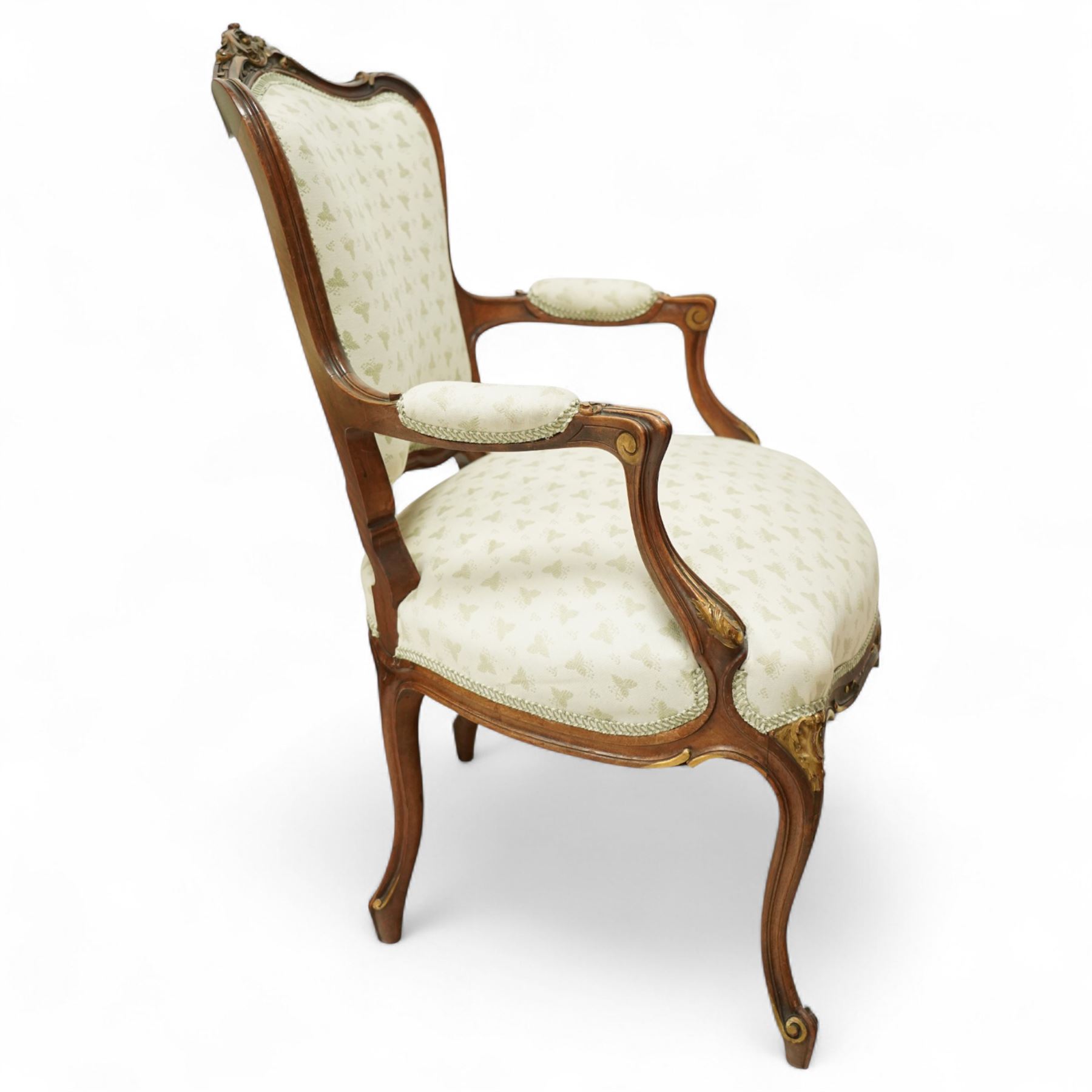 Louis XV design salon suite comprising a pair of walnut and parcel-gilt fauteuil armchairs together with a side chair, the cresting rail surmounted with a carved giltwood floral shell motif with extending foliage, the cartouche shaped backs and sprung seats upholstered in pale blue patterned fabric, over a shaped apron with scallop decoration and foliage carved knees, raised on cabriole supports