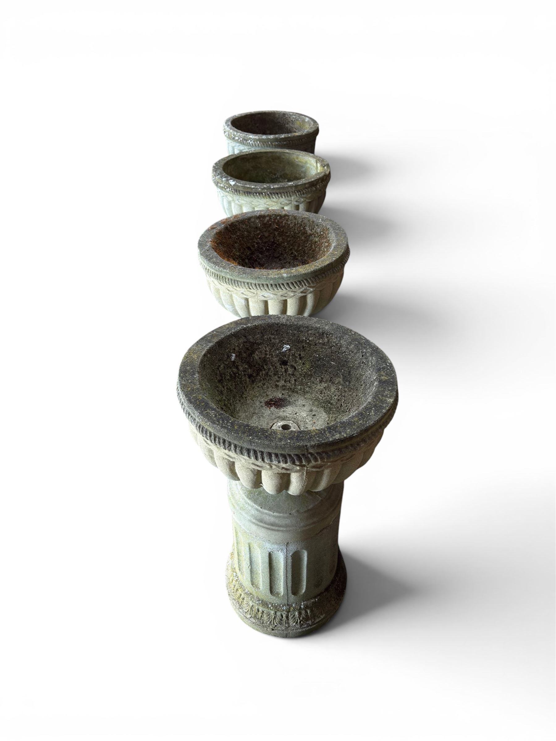 Four 20th century good quality weathered cast stone pedestal urns, circular lobed bowls with rope twist and lattice border, raised on squat base with fluted columns