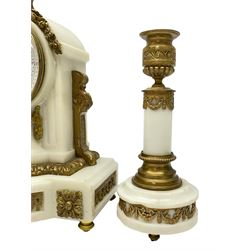 An early 20th century white marble mantle clock in a break front case with an arched top and finial, gilded scroll work to the sides and pierced foliate panels to the front, plinth raised on five bun feet, enamel dial with garland decoration, Arabic numerals, minute markers and Louis XV gilt hands, within a convex glazed bezel, eight-day Parisian striking movement striking the hours and half hours on a bell, with two conforming single light candlesticks. With Pendulum.

