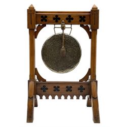 Late Victorian Aesthetic Movement walnut and ebonised dinner gong, the trestle frame with pierced quatrefoil motifs supporting circular hammered bronze gong, splayed angular supports