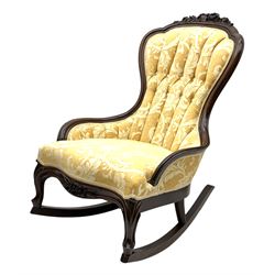 Early 20th century rocking chair with raised floral and foliate carving to frame, upholstered buttoned and fluted back in pale gold patterned chenille fabric