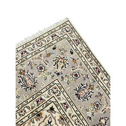 Persian Kashan ivory ground carpet, floral central medallion surrounded by trailing leafy branches and palmettes, floral pattern spandrels and matching border, within guard stripes