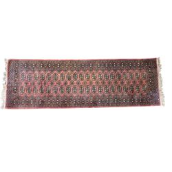 Afghan pale red ground runner, the field decorated with two rows of Gul motifs, within repeating patterned border