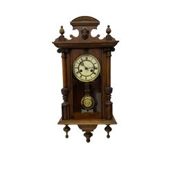 An early 20th century German wall clock with an 8-day HAC spring driven movement striking the hours on a coiled gong, in a mahogany case with a shaped pediment and turned columns flanking a full-length glazed door, with a two-part dial enamel with Roman numerals, minute track and pierced gothic designed hands, gridiron pendulum and beat plate. With Key.





