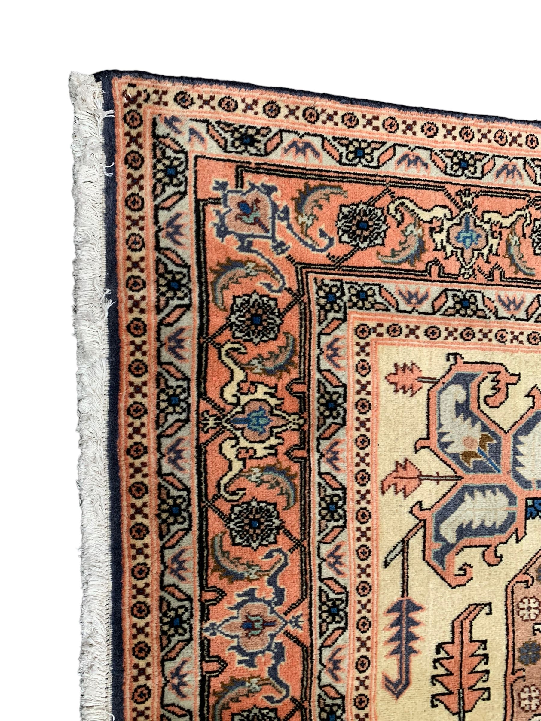 Persian ivory and peach ground, overall geometric design, the field with central star medallion surround stylised leaf motifs, guarded geometric design border