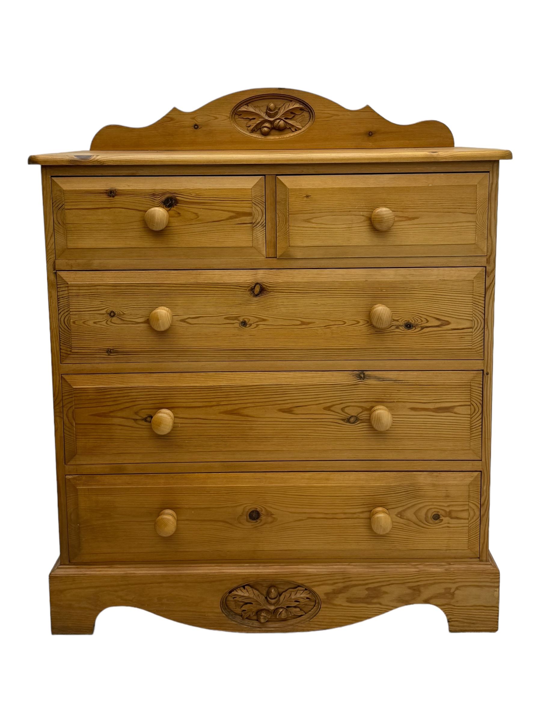 Pine chest of drawers topped with carved pediment with acorn and oak leaf motif, fitted with two short over three long drawers, standing on shaped apron base (W92, D46, H97cm); pine bedside cabinet, single drawer above paneled cupboard door enclosing open storage, shaped plinth base (W43, L32, H67cm)