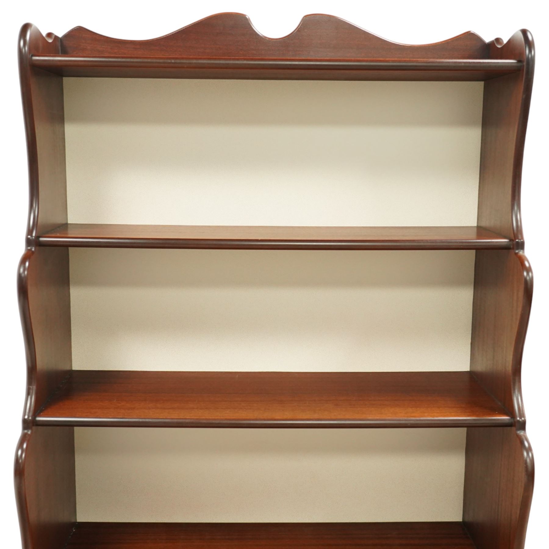 Early 20th century mahogany waterfall bookcase, shaped and serpentine side uprights with scalloped cresting, fitted with four open shelves above two short drawers with brass drop handles, raised on shaped bracket feet