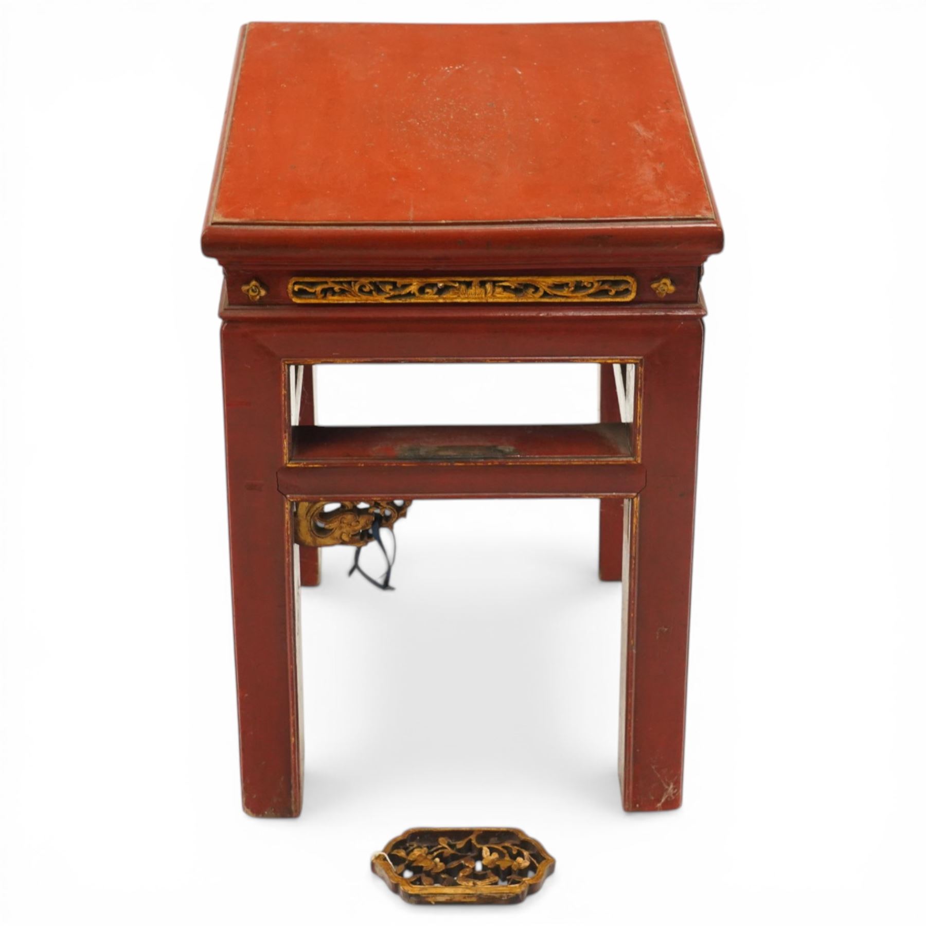 Early 20th century Chinese red lacquered occasional table, rectangular top over a pierced frieze decorated with carved giltwood floral panels and brackets, raised on moulded square tapering supports