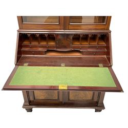 Early 19th century figured mahogany bureau bookcase, projecting splay moulded cornice over three adjustable shelves enclosed by two glazed doors, fall front revealing pigeonholes, cupboard and drawers, pull-out strays with scroll carved terminals, double cupboard with two panelled doors, on turned feet 
