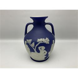 19th century Wedgwood dark blue dipped Jasperware Portland vase, of ovoid form with twin handles to shoulders and waisted neck, and flared rim, the body decorated with a continuous scene of classical figures in relief, the base decorated with portrait in relief, H26cm