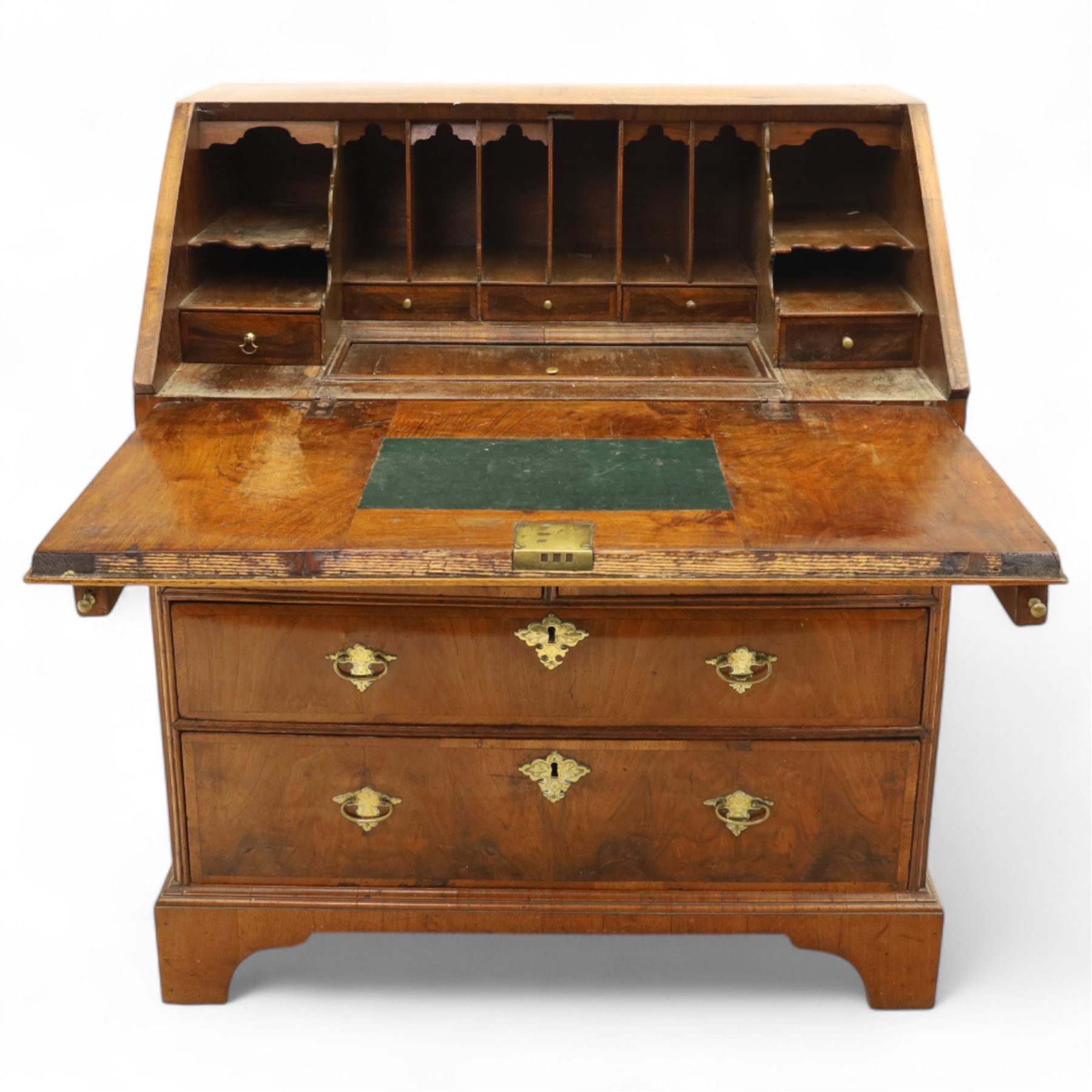 18th century walnut and herringbone banded bureau, the fall front enclosing a stepped and arched interior fitted with pigeonholes, drawers and concealed compartments, green tooled leather writing surface, over two short and three long graduated drawers with brass escutcheons and bail handles, shaped bracket feet