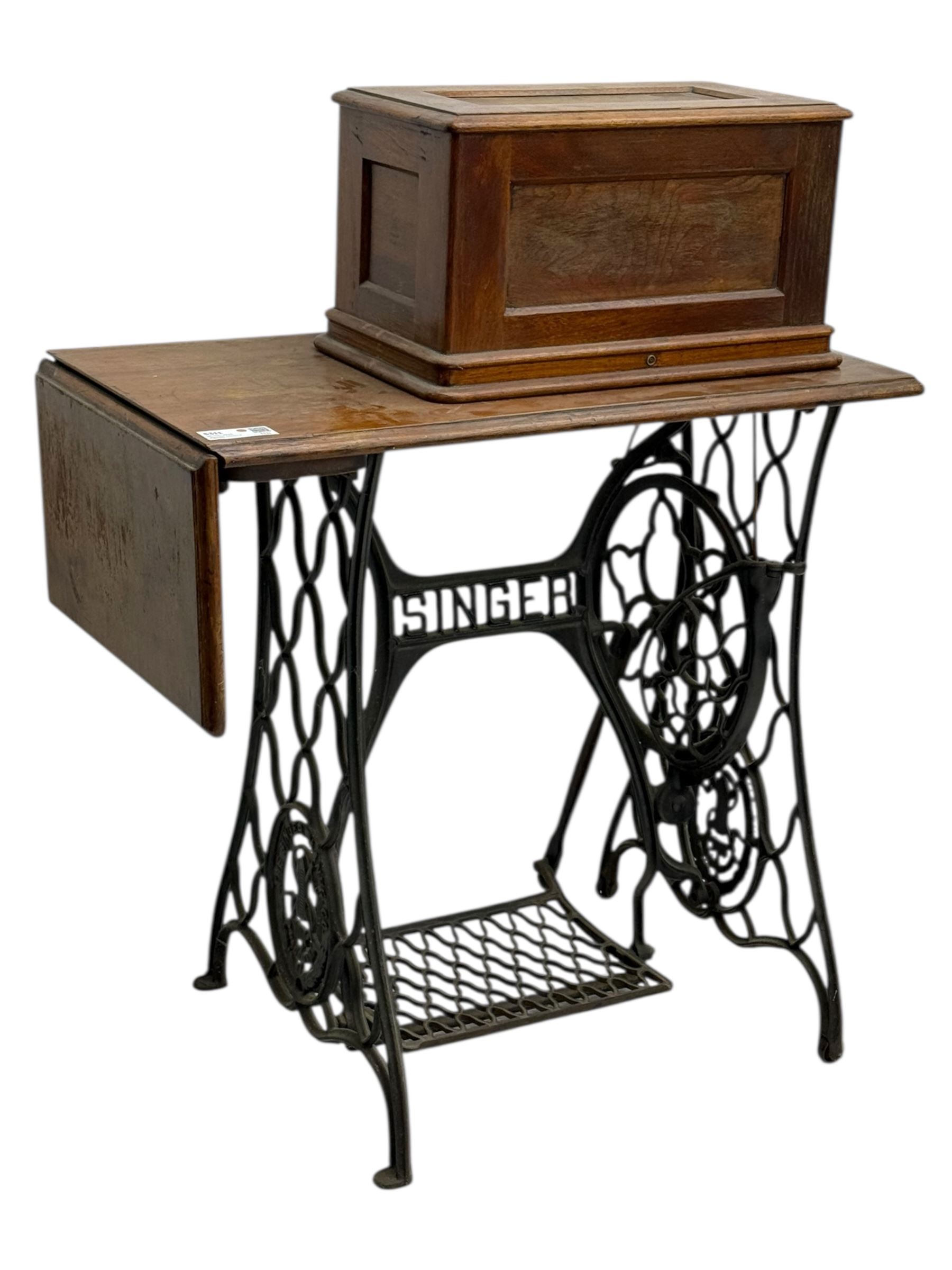 Singer - early 20th century cast iron treadle sewing machine, with hand crank wheel and oak work surface, the machine decorated with gilt foliate detail, complete with rectangular wooden cover and folding extension leaf