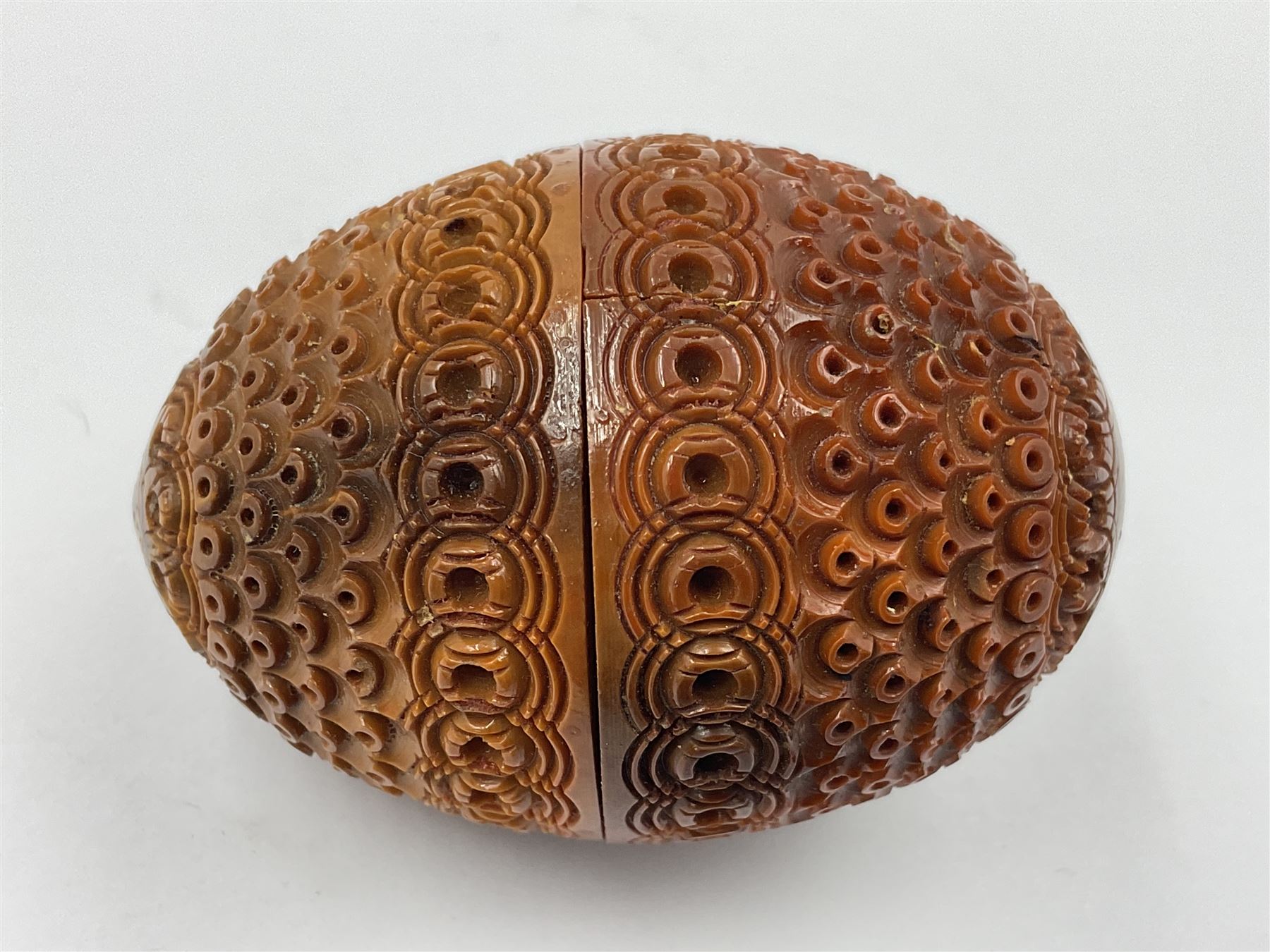 Three 19th century coquilla nut pomanders or flea catchers, two of egg shaped form and the third of barrel from with carved and pierced decoration and screw threaded join, largest H8cm