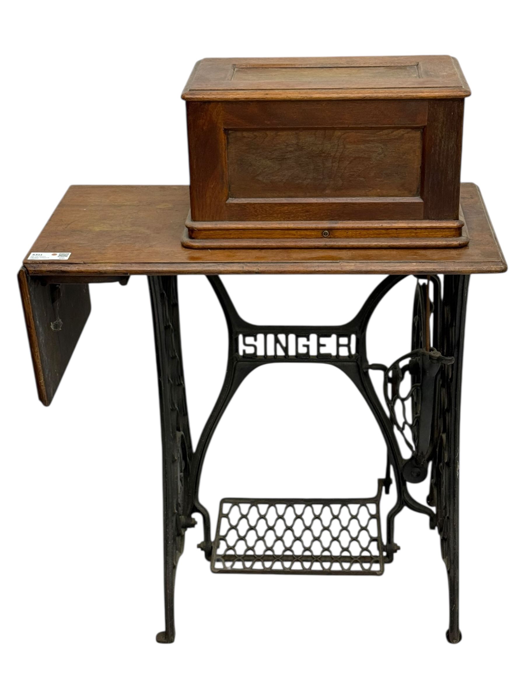 Singer - early 20th century cast iron treadle sewing machine, with hand crank wheel and oak work surface, the machine decorated with gilt foliate detail, complete with rectangular wooden cover and folding extension leaf