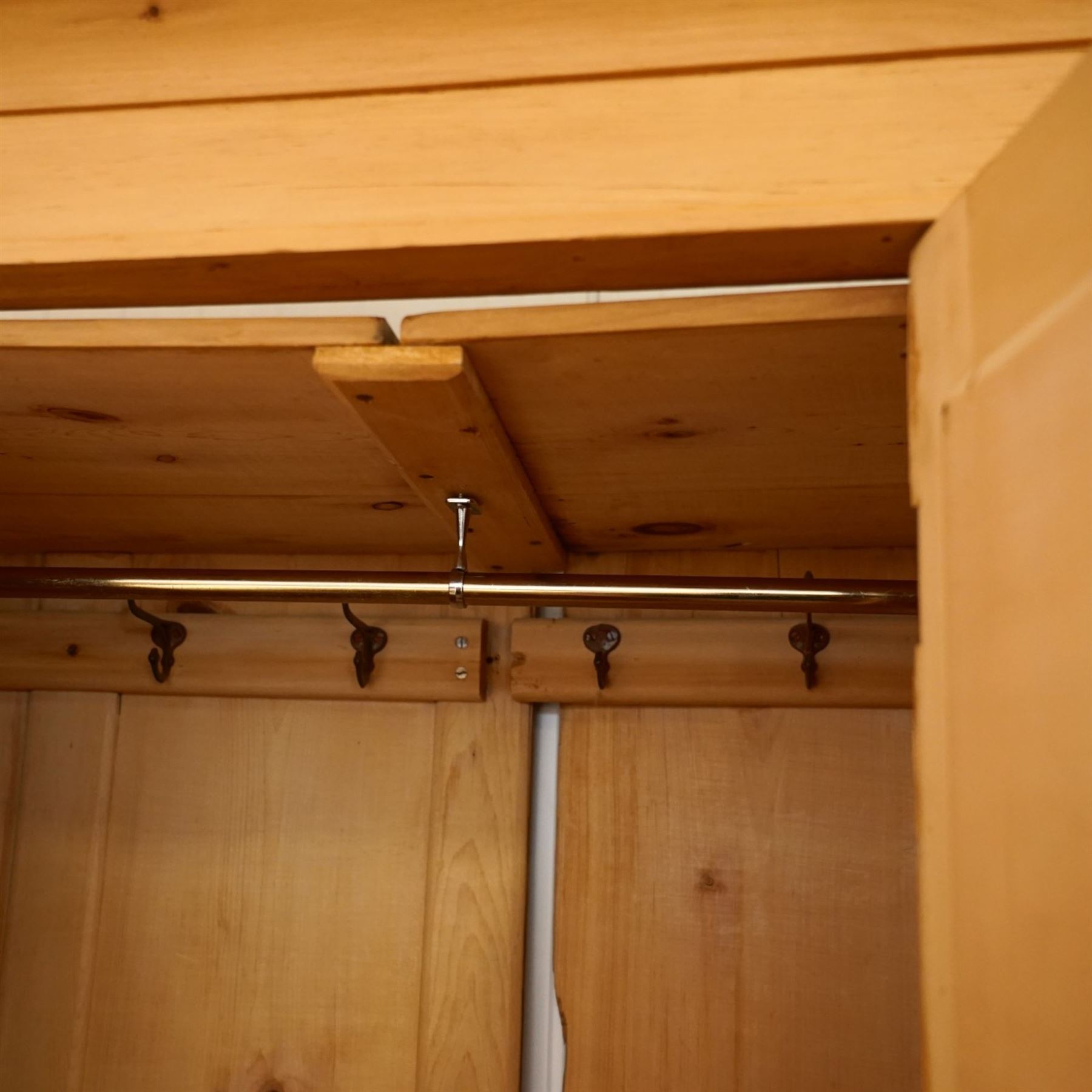 Victorian waxed pine wardrobe, carved projecting cornice with mirrored door, enclosing clothes hooks and rail, above a single drawer with glass knobs