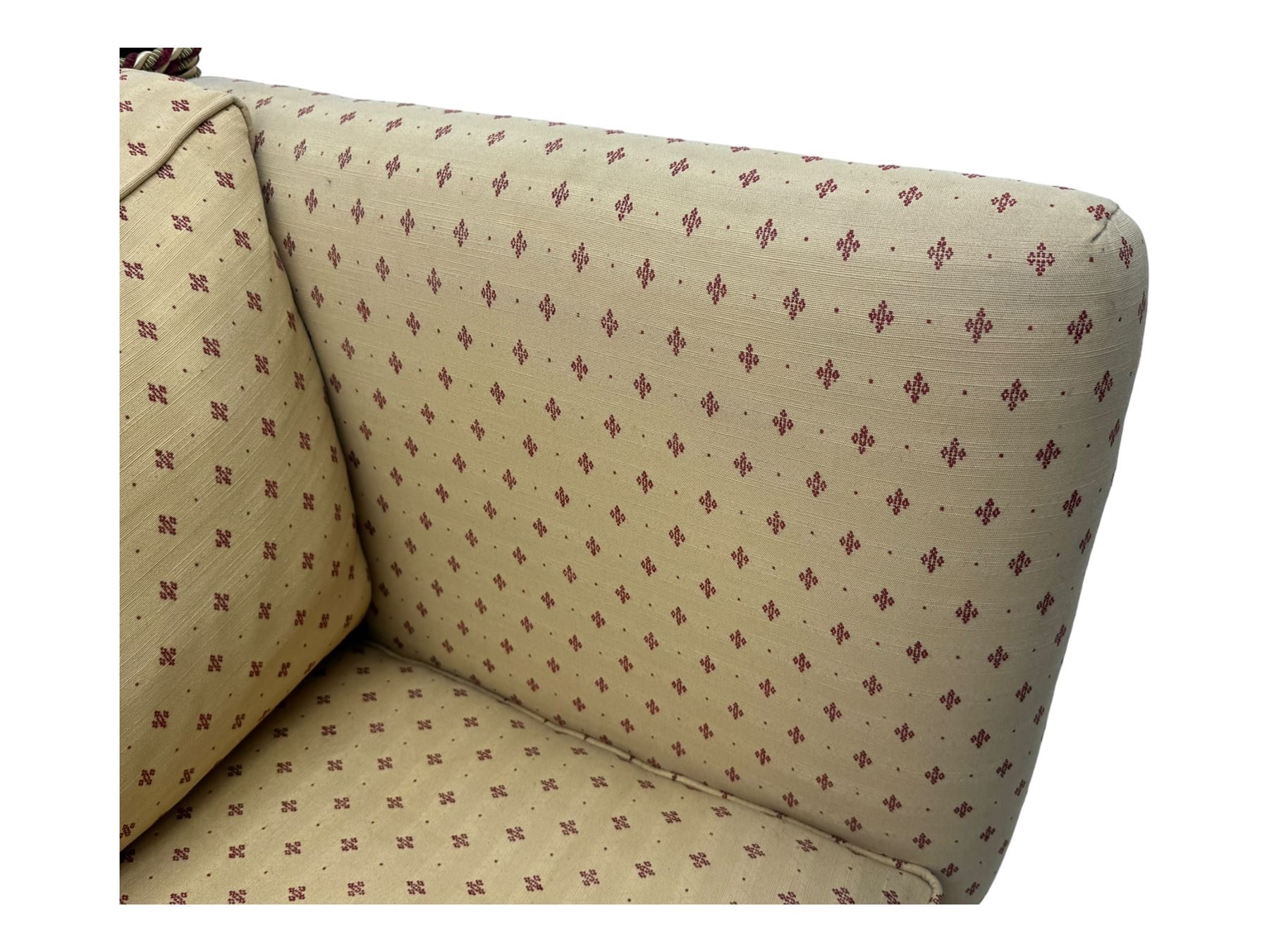 20th century Knole design two seat sofa, high back and double drop-arm joined by mahogany finials and ties, upholstered in camel ground fabric with red lozenge design, on turned supports with brass castors
