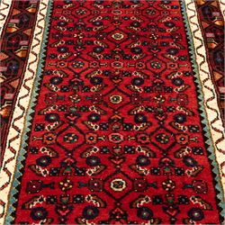 North West Persian Malayer runner, madder red field decorated with an all-over design of stylized herati motifs in shades of indigo, ivory, and green within ivory and dark blue borders of angular vine and rosette design, with cotton fringe ends 