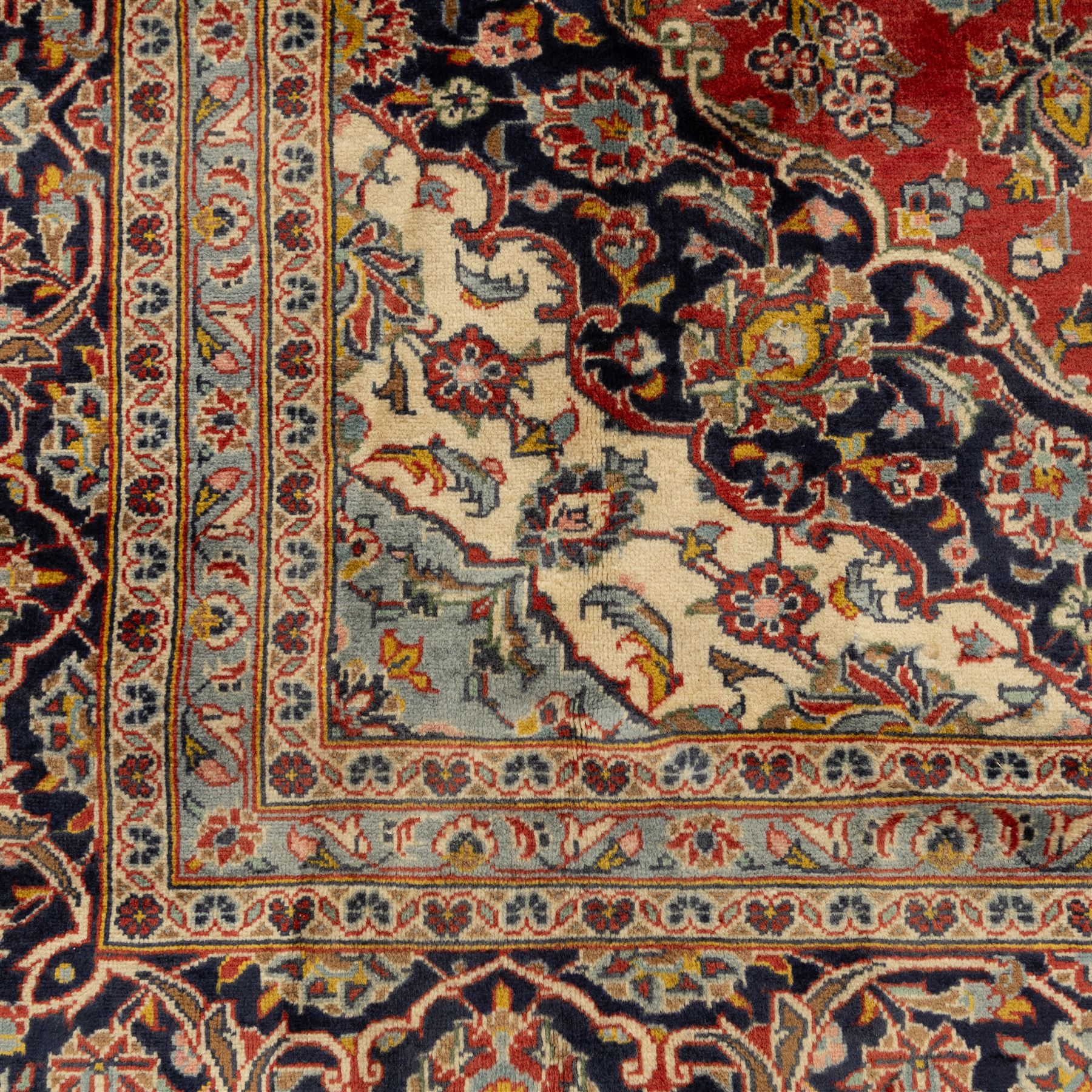 Persian Kashan carpet, the field in rich rust tone centred by an ivory and blue medallion with palmette extensions, surrounded by intricate foliate arabesques and stylised blooms, within triple floral borders incorporating palmettes and interlaced tendrils, woven in the region of Kashan