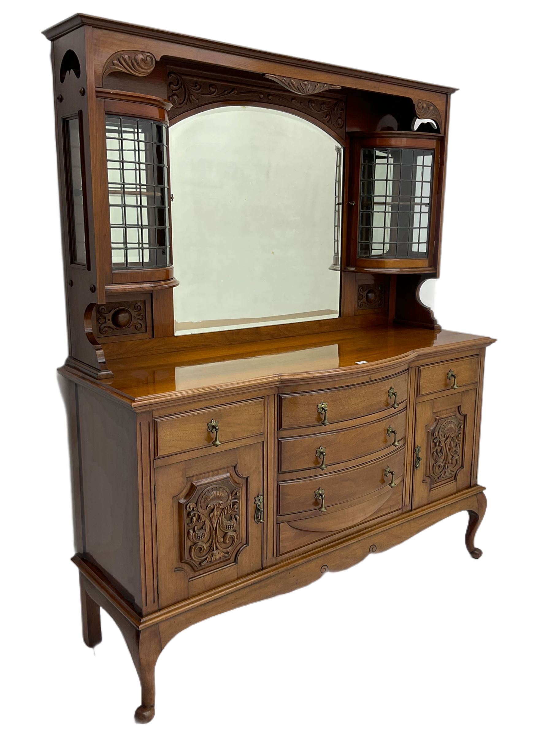 Late Victorian walnut mirror back sideboard or dresser, the raised back fitted with two curved and lead glazed cabinets, central arched bevelled mirror, the sideboard with break bowfront, fitted with six drawers and two cupboards, the cupboard doors panelled and carved with scrolls, shell and plant motifs, shaped apron with cabriole feet
