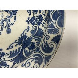 Early 18th century Delft marriage plate, of circular form with dished centre, the centre inscribed and dated 'Thomas and Elizabeth Kockerill Bridlington Key 1715' within a crowned C scroll cartouche, flanked by demi-griffins, above a putto head and tassels, within a wide foliate border, D34cm
