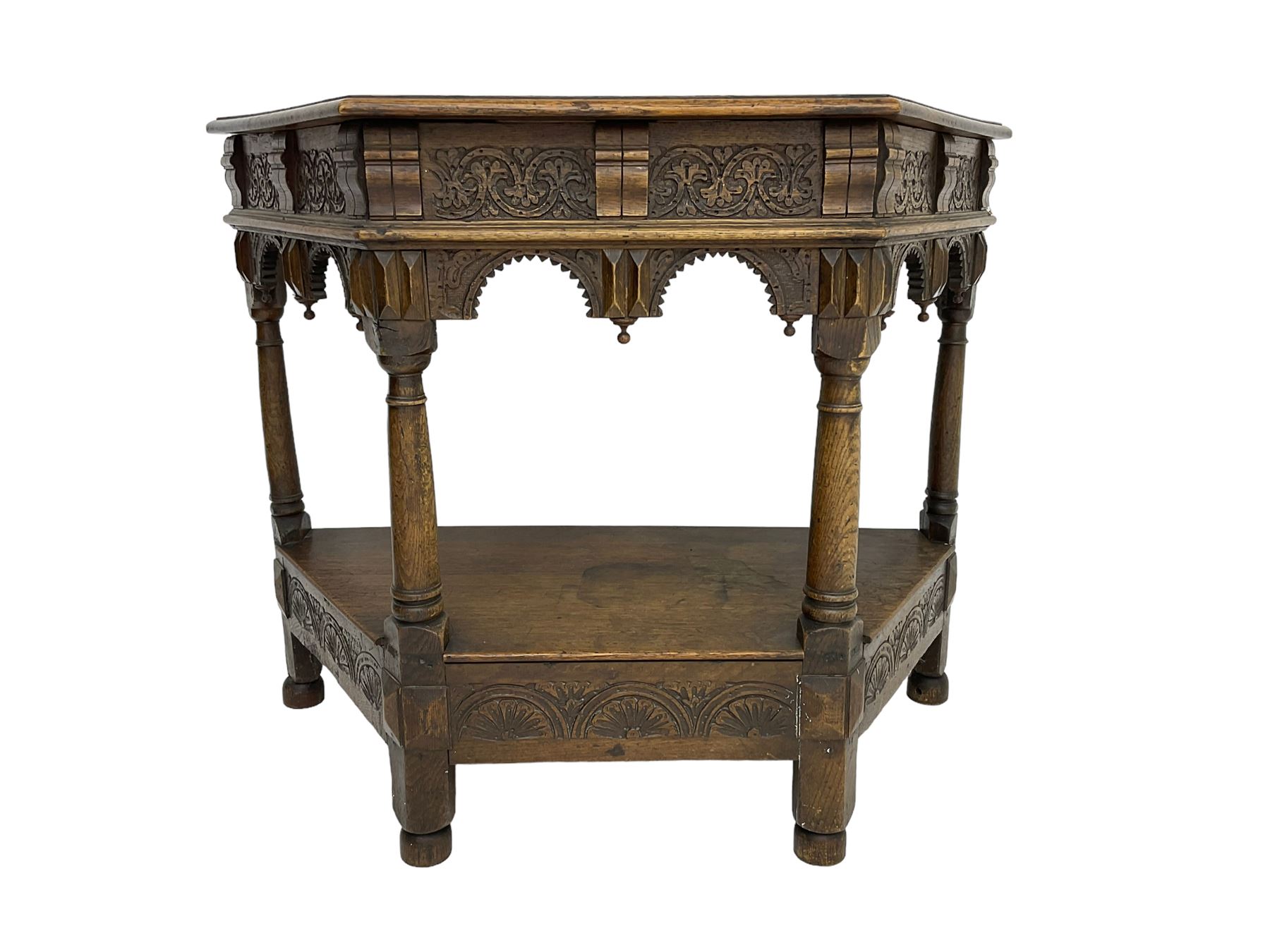 Jacobean design carved oak side or credence table, demi-heptagon top with moulded edge, frieze carved with foliate C-scroll design above ornate arcade carved apron, under-tier united by ring turned pilisters, lower frieze carved with repeating lunettes