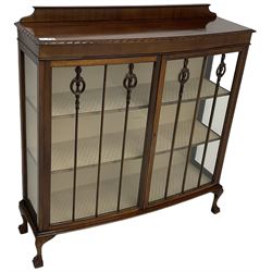Early 20th century mahogany bow-front display cabinet, enclosed by two glazed doors, on ball and claw feet