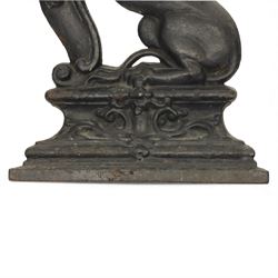 Victorian cast iron figural doorstop in the form of a lion, depicted seated with curled tail and detailed mane, raised foreleg resting against a scroll motif, set on an integral stepped base with moulded edges and foliate ornament