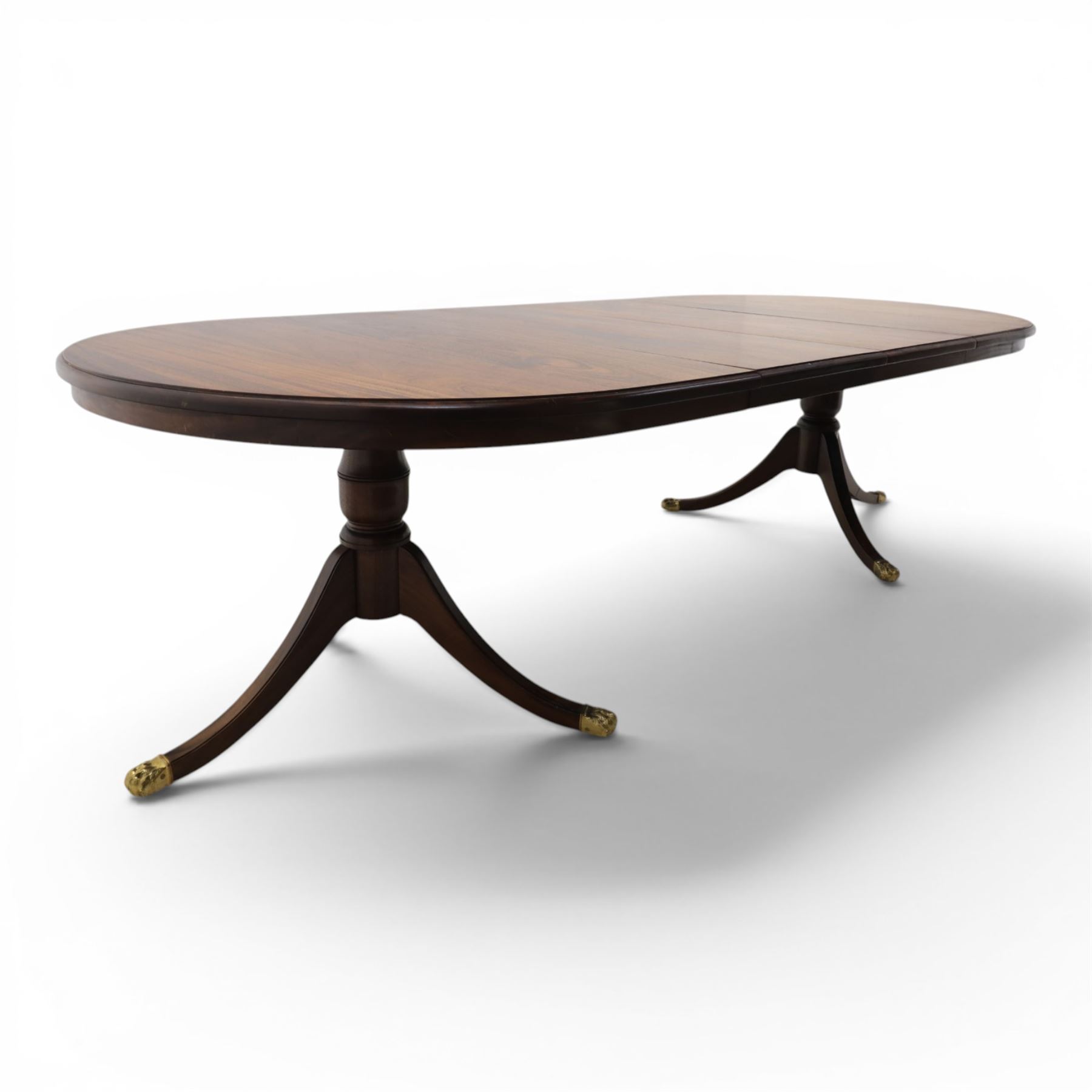 Regency design mahogany extending twin pedestal dining table with two additional leaves, raised on splayed supports terminating brass paw feet
Extends to 268cm