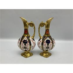 Pair of mid 20th century Royal Crown Derby Imari 1128 pattern Kedleston ewers, each with gilt scroll handle and neck, upon a gilt quatrefoil foot, each with printed marks beneath, H25.5cm