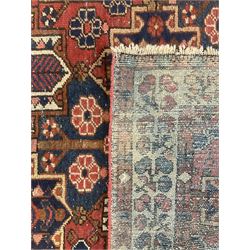 Persian crimson ground rug, the field decorated with three rows of stylised plant medallions and small flowerhead motifs, repeating floral design border with guards 