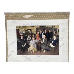 Photograph of the cast of Heartbeat posing in costume in the Aidensfield Arms and signed by twelve cast members including John Duttine, Tricia Penrose, Clare Wille, Derek Fowlds, Gwen Taylor, Lisa Kay, Peter Benson etc; unframed