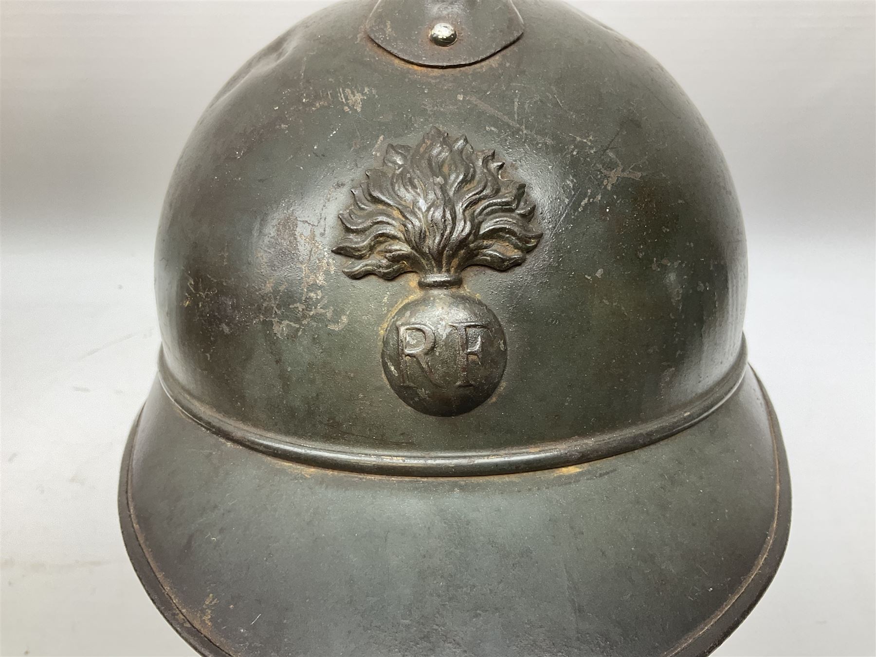 WW2 French M-26 Adrian Pattern Steel Helmet, original olive drab paint finish; flaming grenade badge to the front signifying issue to an Infantry regiment; original leather liner and leather chinstrap; and WW2 Dutch steel helmet with liner and chin strap (2)