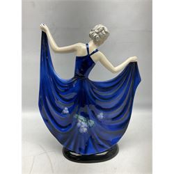 20th century American Goldscheider Art Deco figure, female in blue dress decorated with vines and grapes, holding up her skirts by the hem, on oval base, by Stefan Dakon, printed factory marks to base, impressed 8126 11 14, H40cm