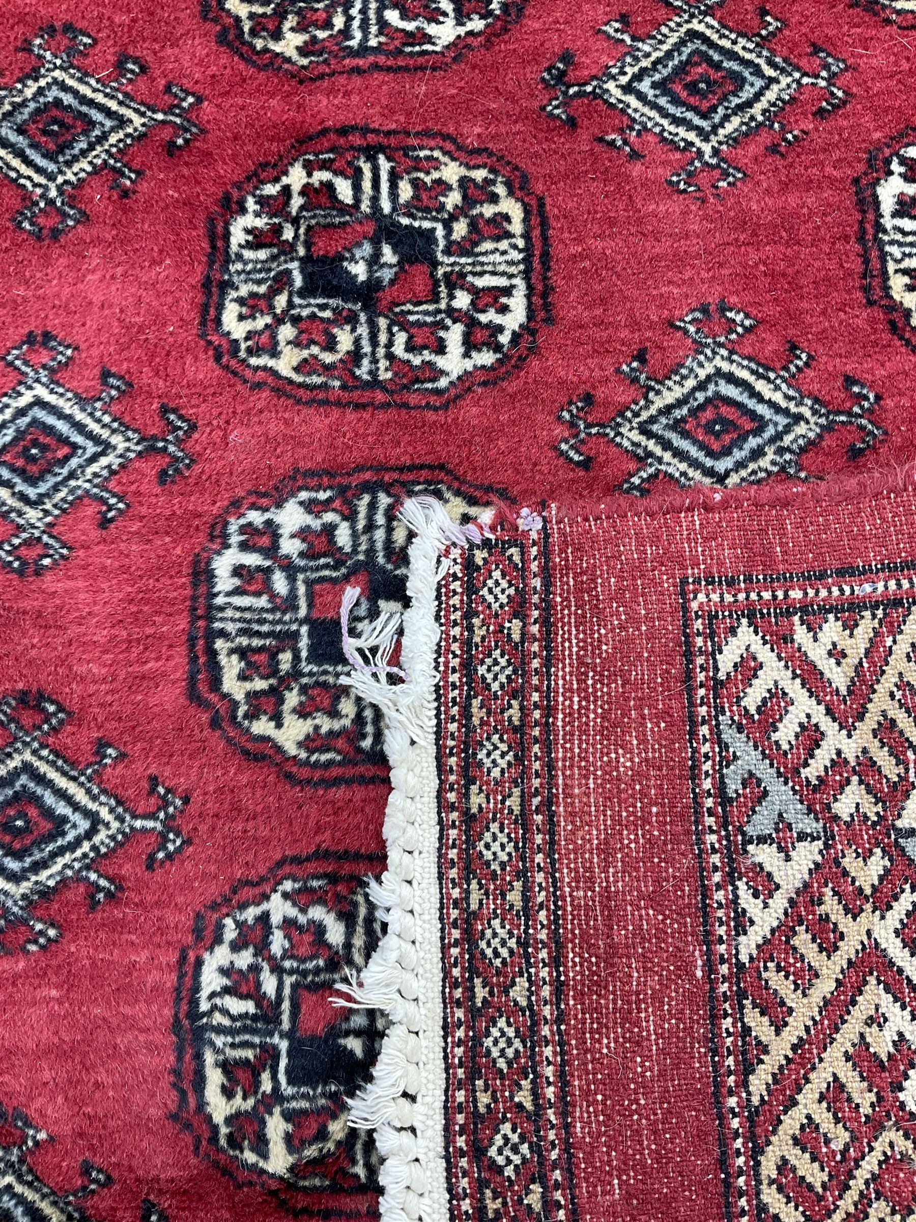 Turkmen Tekke Bokhara rug, red ground and decorated with Gul motifs, repeating multi-band border, signed on corners 
