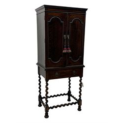 Early 20th century oak two-door cabinet, with single drawer, interior with four fixed shelves on raised barley twist stand 
 