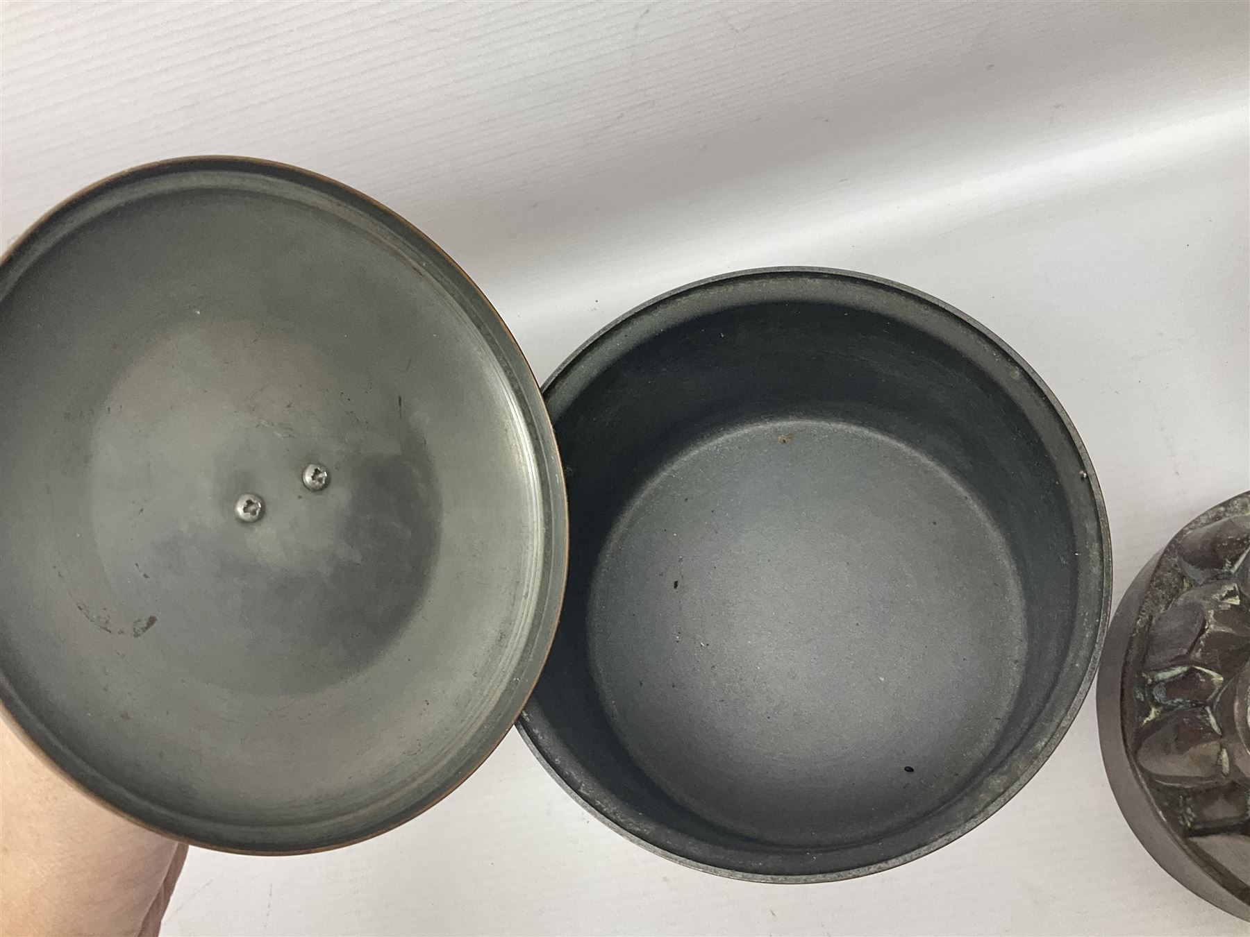 Four Victorian copper moulds, together with a graduating set of copper pans with wooden handles and finials to covers, largest pan 