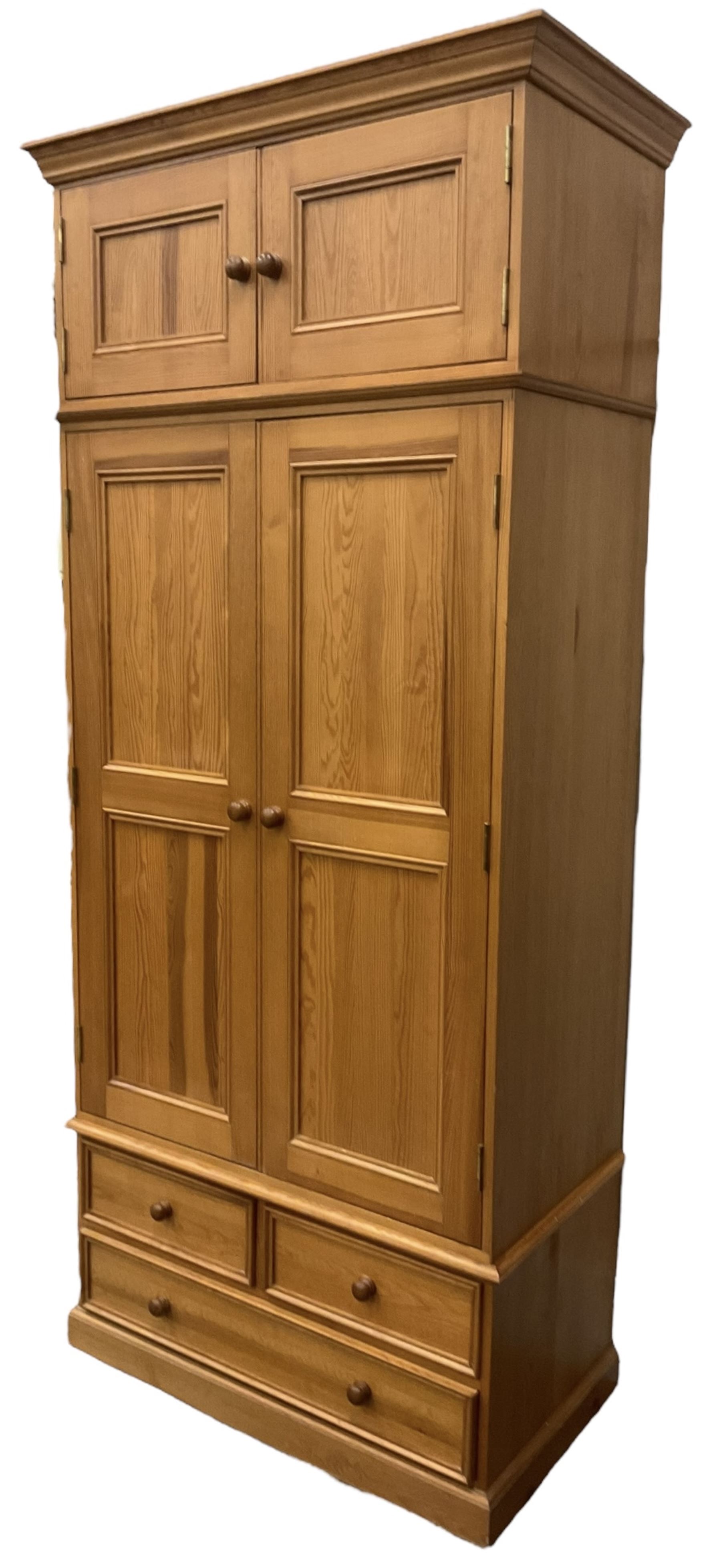 Solid pine double wardrobe, fitted with top box, enclosed by panelled doors, two short and one long drawer, on plinth base 