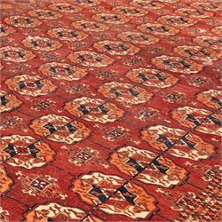 Persian Bokhara crimson ground rug, the field decorated with five rows of repeating Gul motifs with interspersed geometric design, enclosed by a guard band of further geometric-style Gul designs comprised of hook motifs