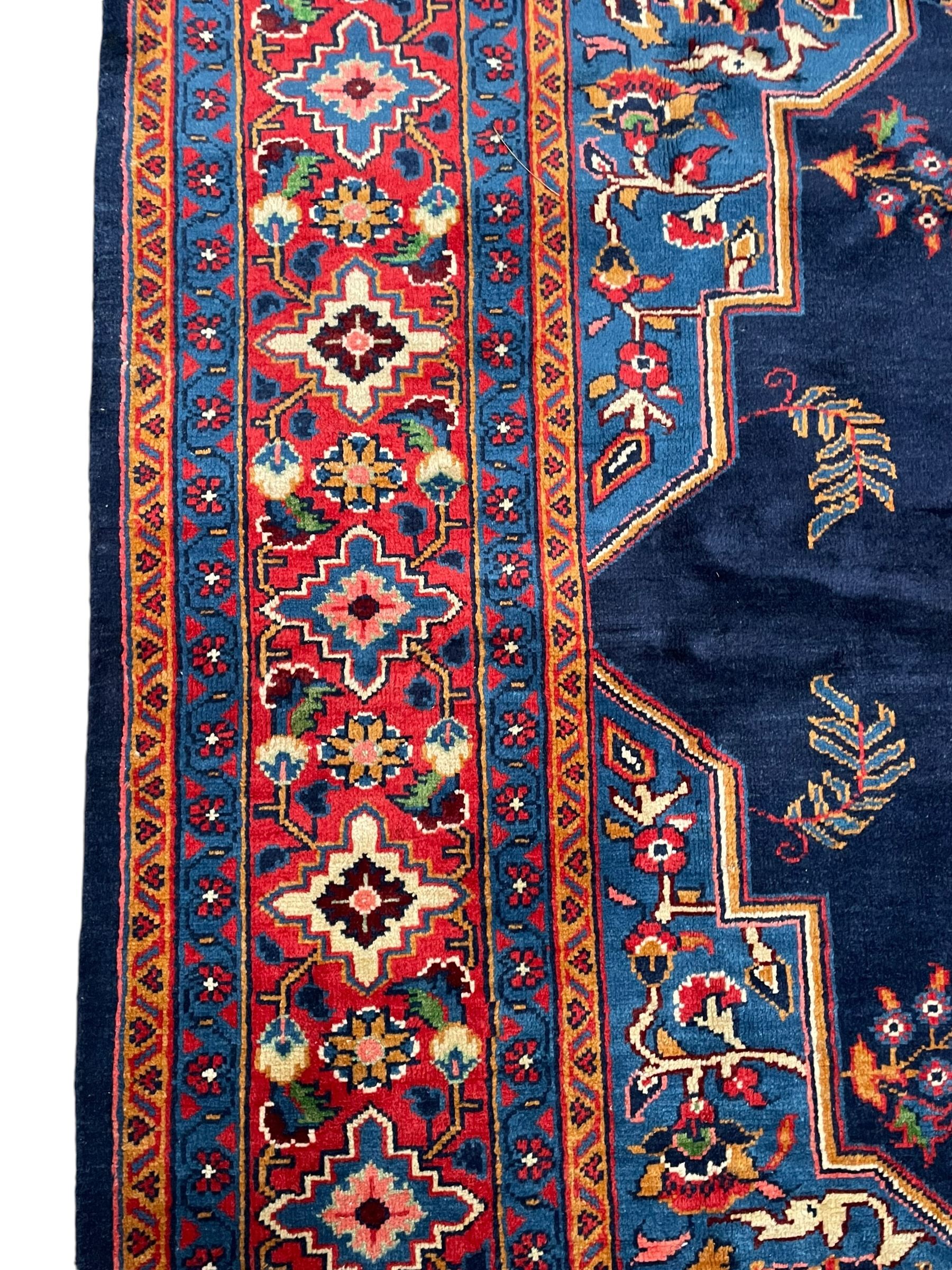 Persian Veis indigo ground carpet, the field with large pole medallion decorated with Herati motifs and surrounded by floral sprays, crimson ground border with repeating cross motifs and stylised flower heads, within guard stripes 