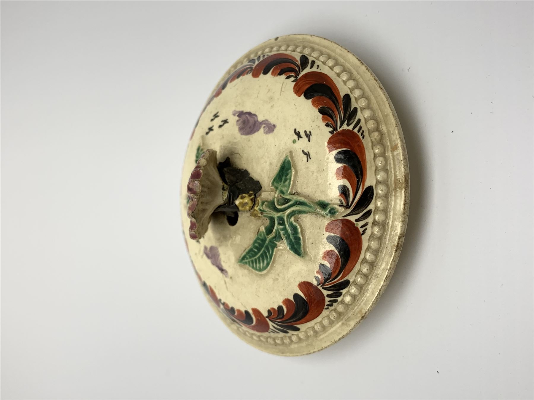 18th century creamware teapot, probably Leeds, with reeded entwined handle and floral finial to the cover, the body with hand painted polychrome decoration of figure to one side, and floral spray to the other, collectors paper label beneath inscribed Leeds Pottery, H11.5cm