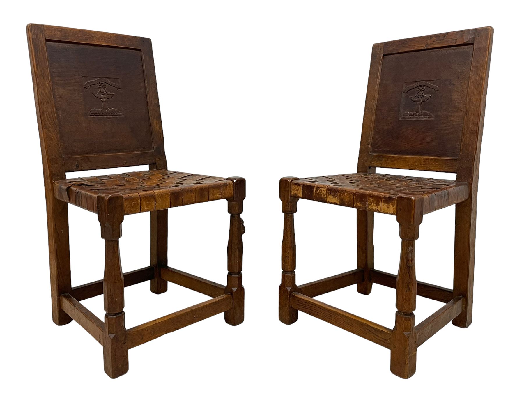 Mouseman - circa. 1930s set of six (4+2) oak dining chairs, panelled back carved with the Bagshawe family crest, the moto 'Forma Flos Fama Flatus' over an arm grasping a bugle-horn with ribbon tie and Yorkshire rose motif, adzed frame, leather lattice strap seat, on octagonal supports united by stretchers, two carvers and four side chairs, each carved with mouse signature, by Robert Thompson of Kilburn 

Provenance: Owned since manufacture by the Bagshawe family, descendants of the Staithes Group Artist Joseph Richard Bagshawe RBA (1870-1909).