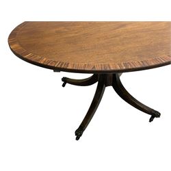 George III mahogany breakfast table, the oval top with a kingwood band and boxwood stringing, raised on a turned vasiform pedestal terminating in a fluted sabre tripod base with hairy paw feet and castors