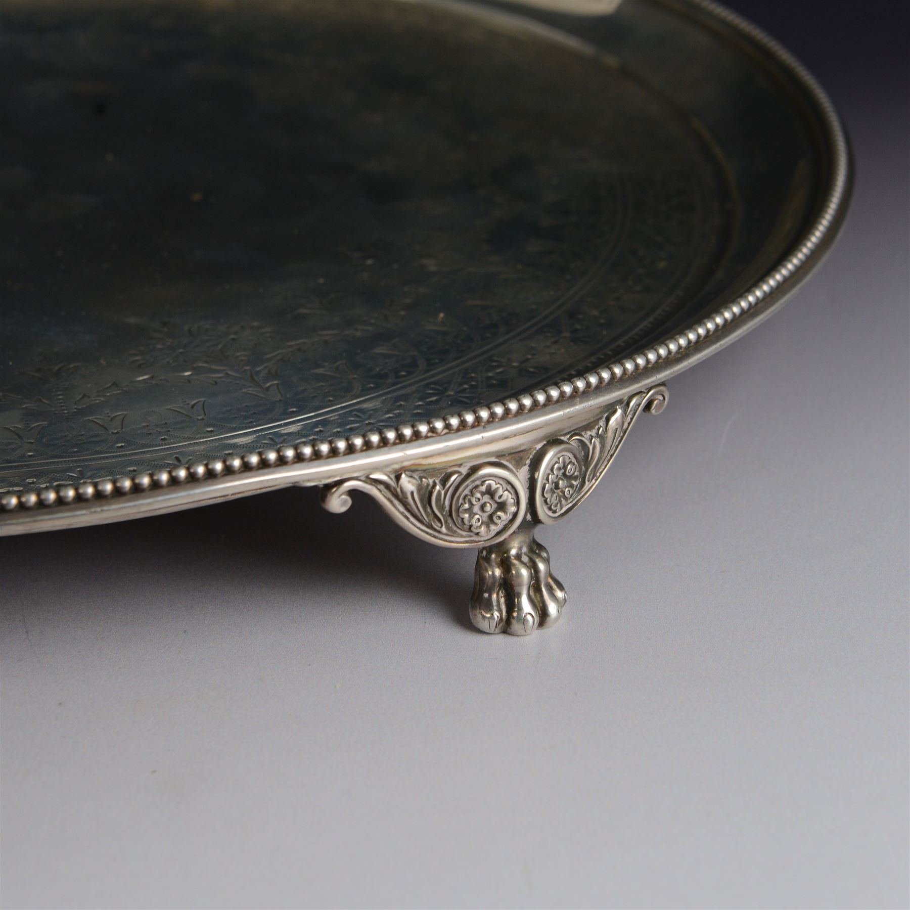 Victorian silver tray, of circular form with beaded rim, engraved to the centre with floral decoration, upon three scroll mounted paw feet, hallmarked Walter & John Barnard, London 1877, D30.5cm