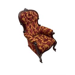 Late 19th century mahogany framed spoonback armchair, cresting rail carved with central cartouche, the scrolled arm terminals supported by foliate carved supports terminating in castors, upholstered in deep red and orange foliate patterned fabric with sprung seat