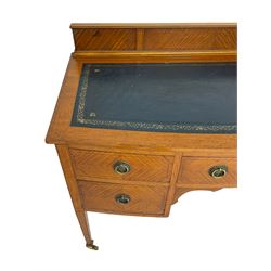 Edwardian satinwood knee-hole writing table or desk, raised back over blue leather inset, fitted with five drawers, each with quarter-veneered fronts, shaped corner brackets, on square tapering supports with brass cups and castors