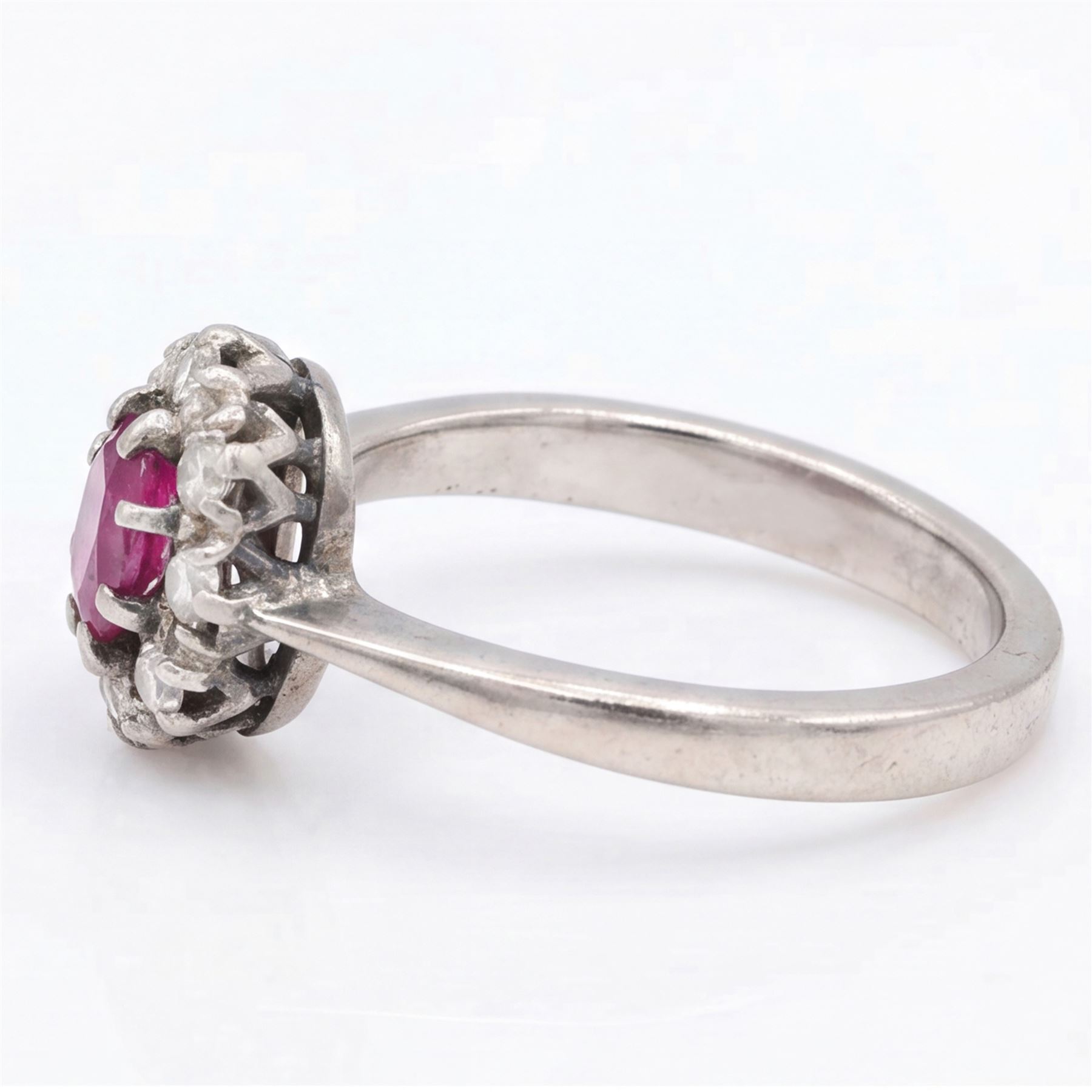 White gold ruby and diamond cluster ring, single oval cut ruby of approx 0.45 carat, surrounded by eight single cut diamonds, stamped 18ct, total diamond weight approx 0.15 carat