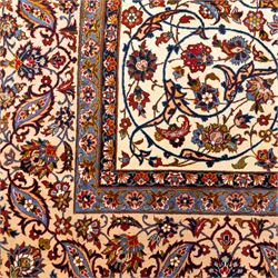Central Persian Najafabad hand-knotted carpet, ivory field with an all-over scrolling floral design of palmettes, rosettes, and leafy vine work, enclosed by a wide floral main border flanked by multiple guard borders in madder red, indigo blue, green, and pale ochre, with cotton fringe ends 
