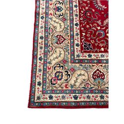 Persian crimson ground carpet, the central foliate pole medallion within a field of palmettes and scrolling branches with matching spandrels, multi-band ivory border decorated with repeating plant motifs